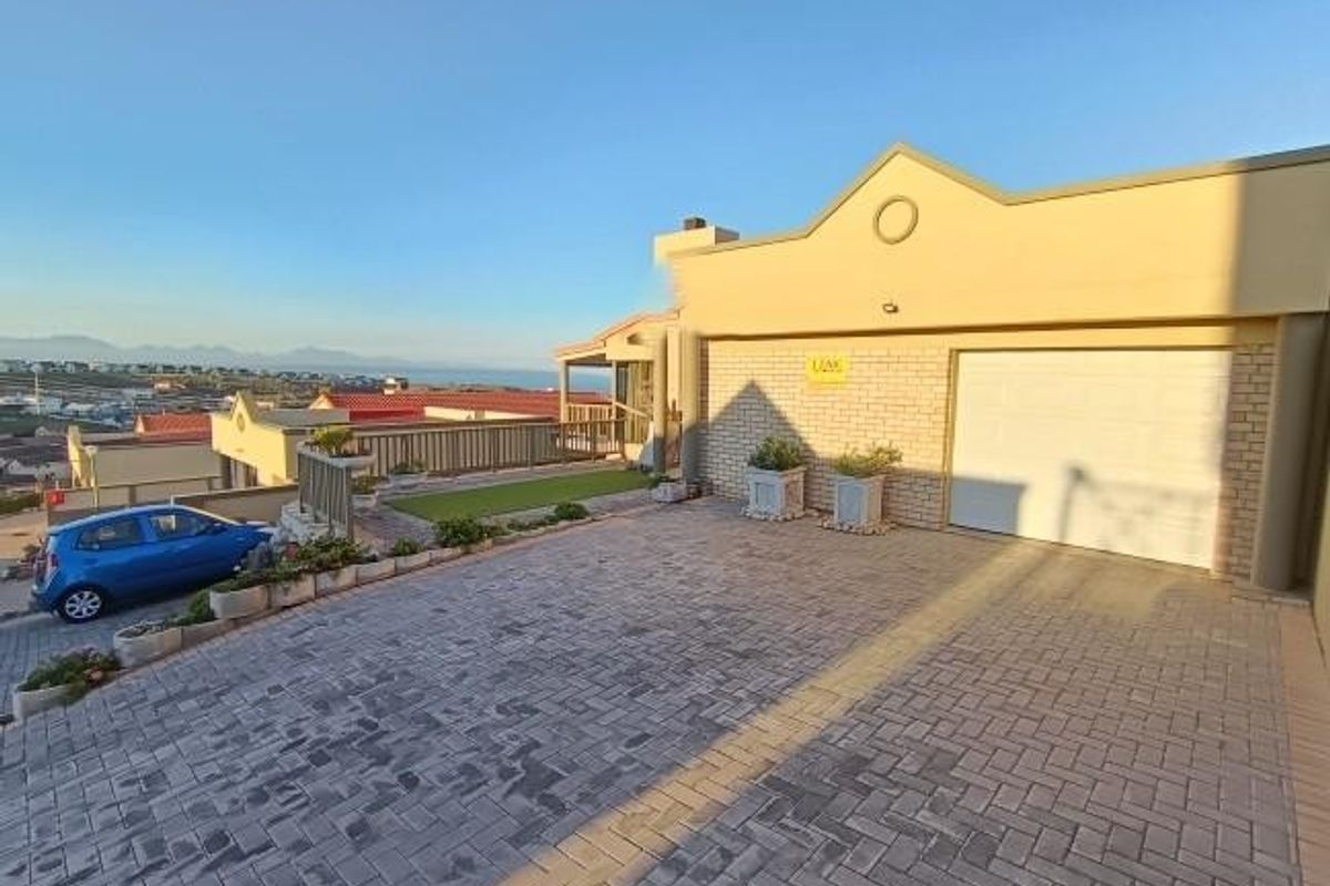 Front exterior view of the property featuring a paved driveway, single garage, and elevated terrace area with coastal views.