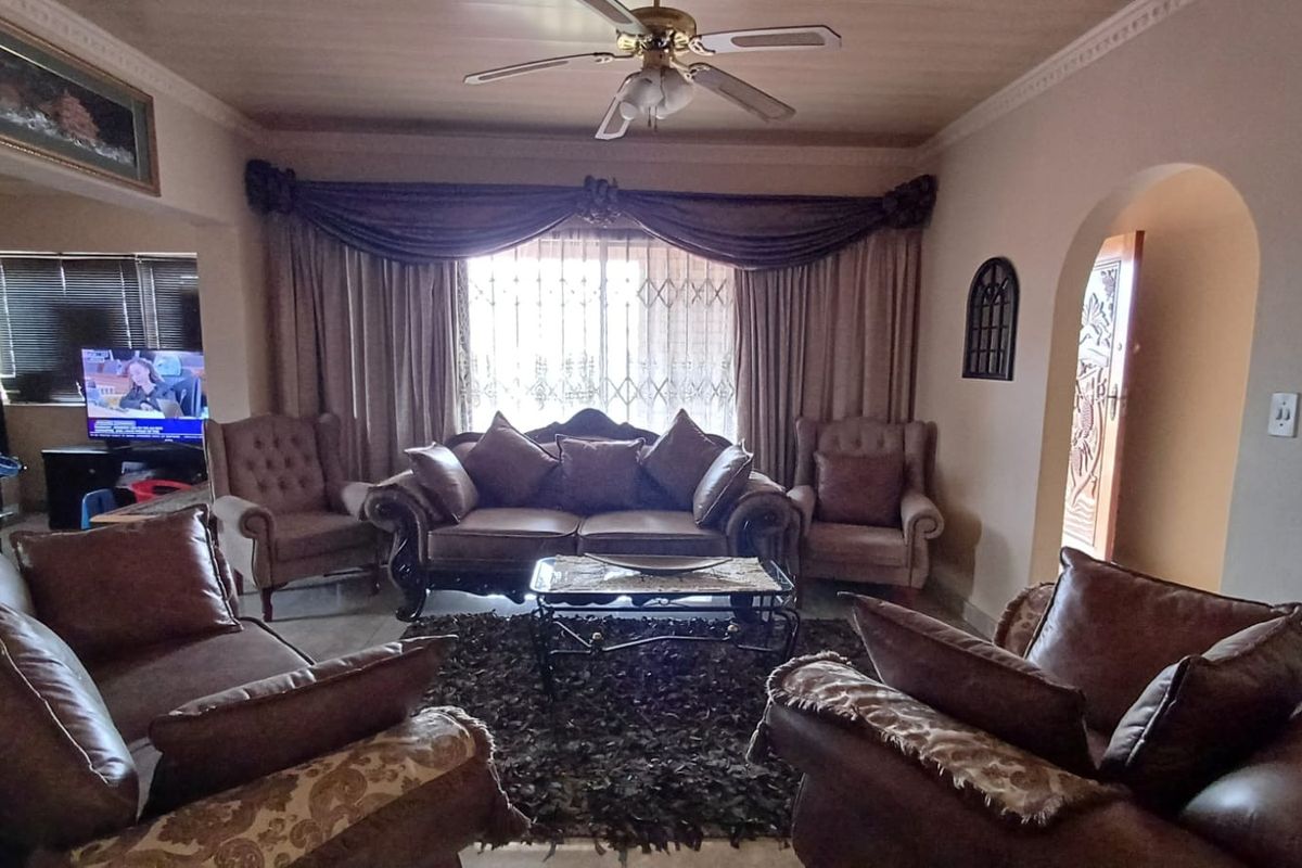A spacious living room featuring a ceiling fan, decorative cornicing, and an arched doorway leading to adjacent areas.