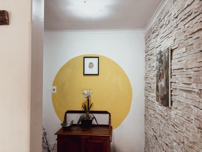 A hallway featuring a textured stone veneer accent wall and a painted circular feature on the adjacent wall.
