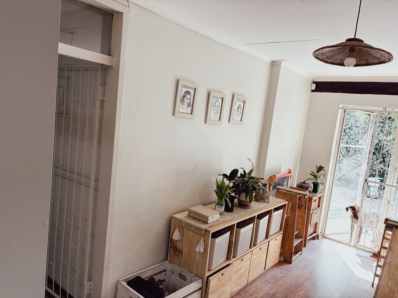 A bright living area featuring laminate flooring, a sliding glass door leading to the garden, and a secure internal gate.