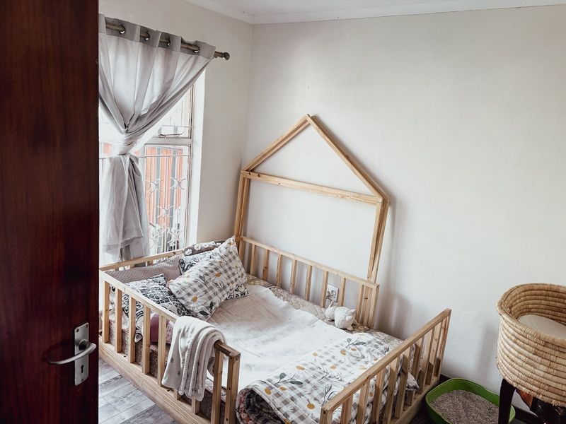 A cozy bedroom featuring a window with security bars, providing natural light and a functional layout.