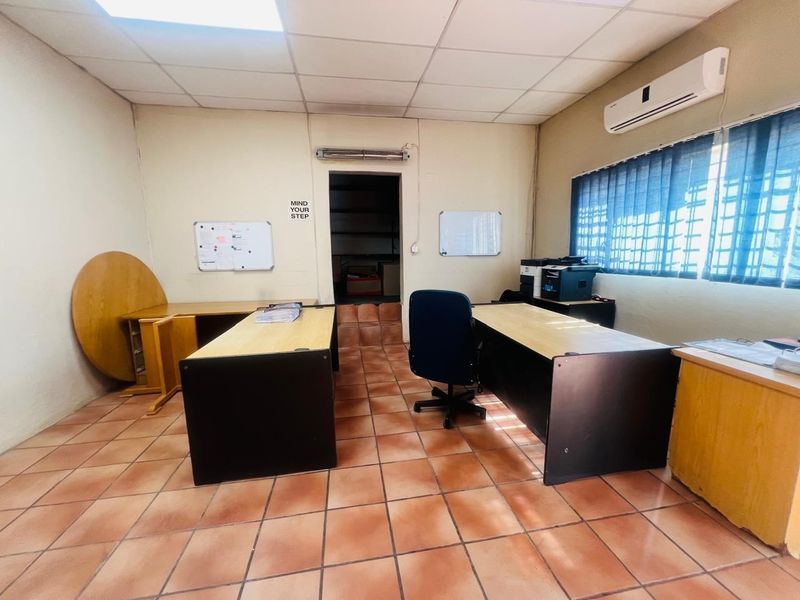 Functional commercial office space featuring ceramic tile flooring, a suspended ceiling, and a wall-mounted air conditioning unit.