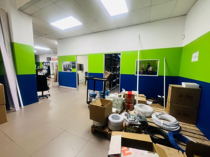 Commercial office space featuring tiled flooring, suspended ceiling with recessed lighting, and internal windows connecting to adjacent work areas.