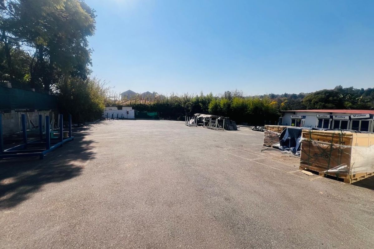 A large, open-air paved commercial yard area featuring perimeter fencing and modular office structures, suitable for storage or logistics operations.