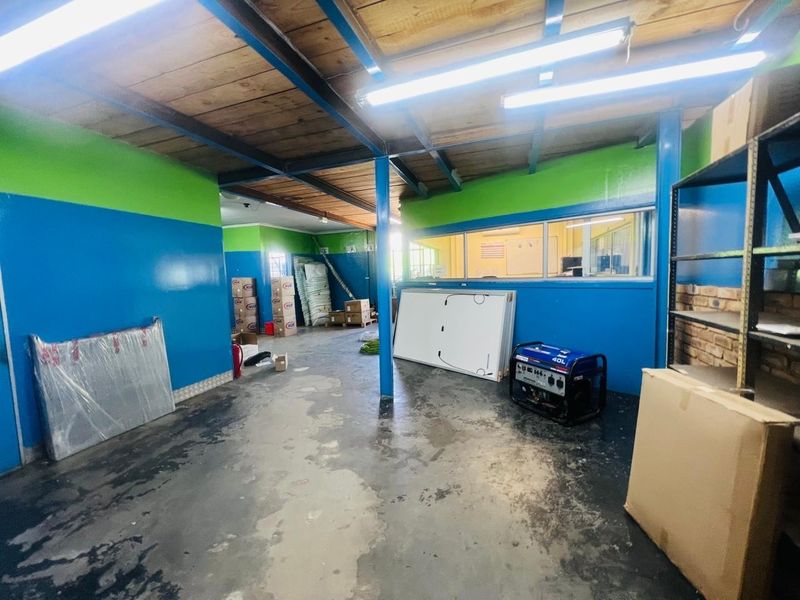 A functional utility or storage space featuring exposed timber ceilings, steel structural beams, and an internal glass partition overlooking an adjacent office area.