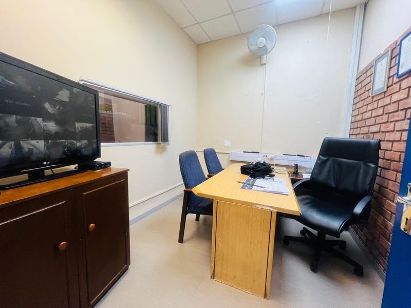A functional commercial office space featuring an exposed brick accent wall, suspended ceiling, and integrated electrical trunking for workspace connectivity.