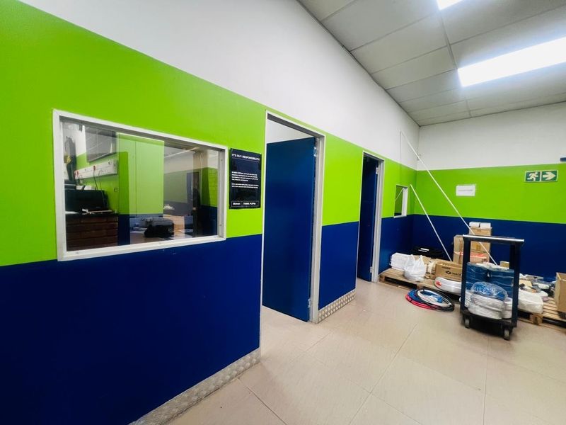 A functional utility or office support space featuring tiled flooring, suspended ceilings, and high-contrast painted walls with internal viewing windows.