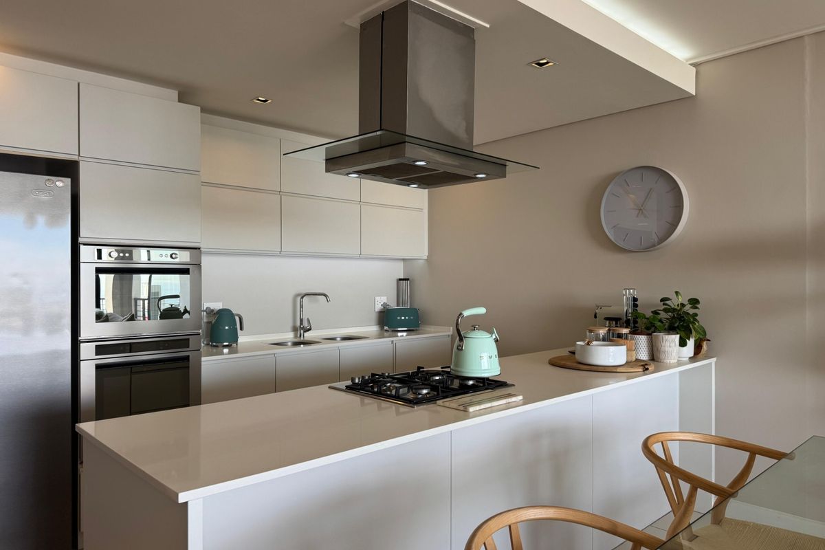 Modern kitchen featuring sleek white cabinetry, quartz countertops, a central island with a gas hob, and high-end integrated appliances.