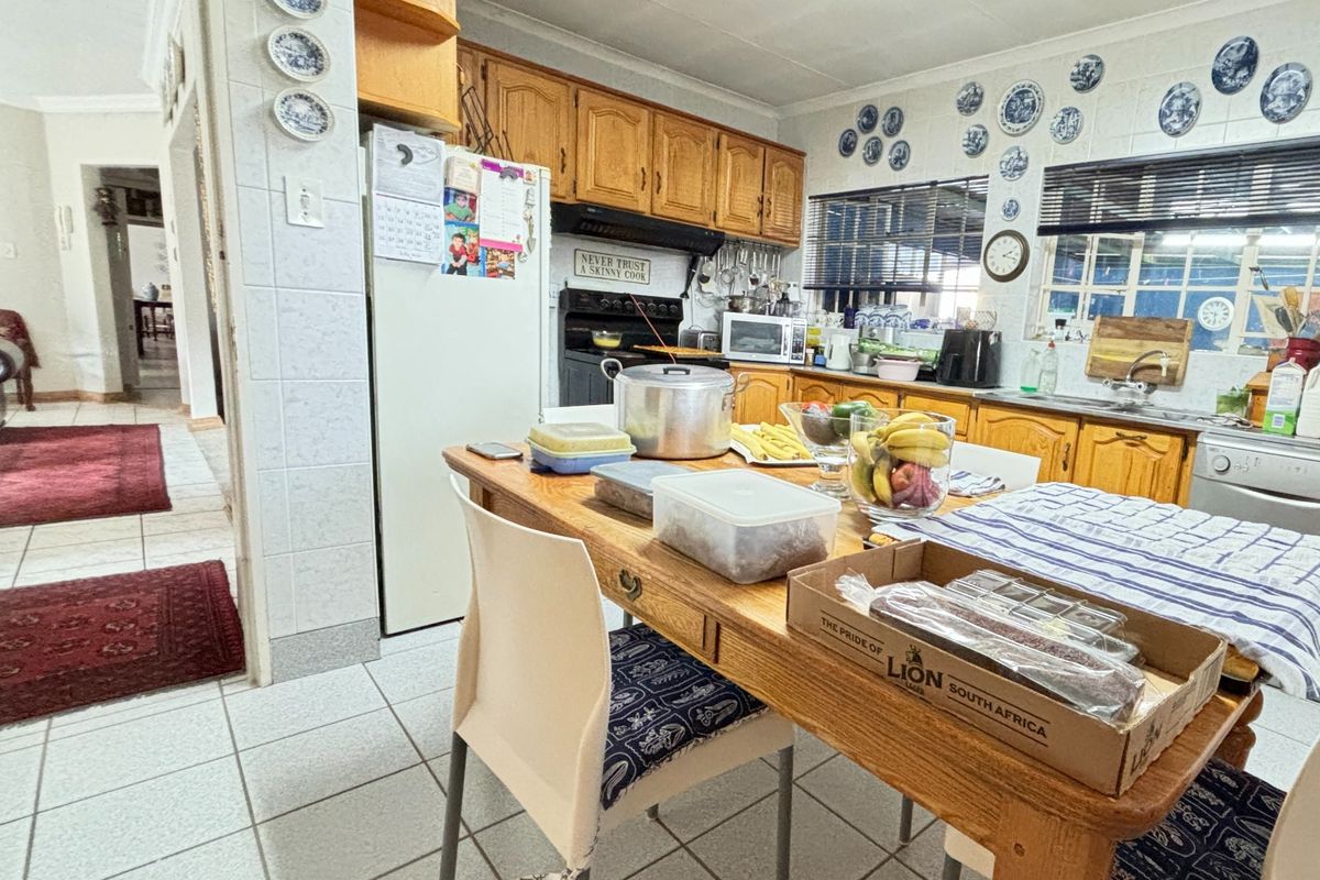 A functional kitchen featuring traditional wooden cabinetry, tiled flooring, and a tiled backsplash, offering a classic layout with integrated cooking and cleaning facilities.