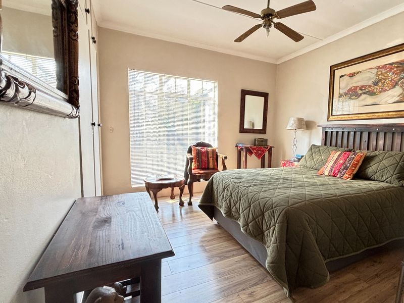 A well-lit bedroom featuring laminate flooring, built-in cupboards, and a ceiling fan, offering a comfortable and functional living space.