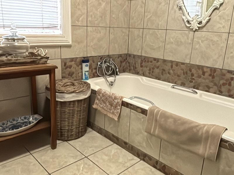 A bathroom featuring a built-in bathtub with tiled surround and flooring, offering a functional space with neutral finishes.