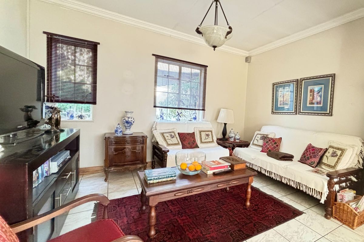 A comfortable living room featuring tiled flooring, crown molding, and natural light through venetian blinds, providing a functional and inviting space.
