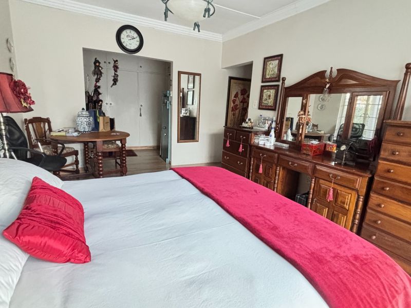 Spacious bedroom featuring built-in cupboards, crown molding, and neutral wall finishes, offering a comfortable layout with ample storage space.