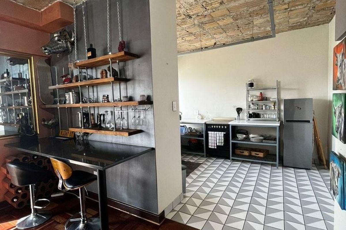 Open plan kitchen and dining area featuring industrial-style exposed brick ceilings, a mix of parquet and geometric tile flooring, and a built-in breakfast bar.