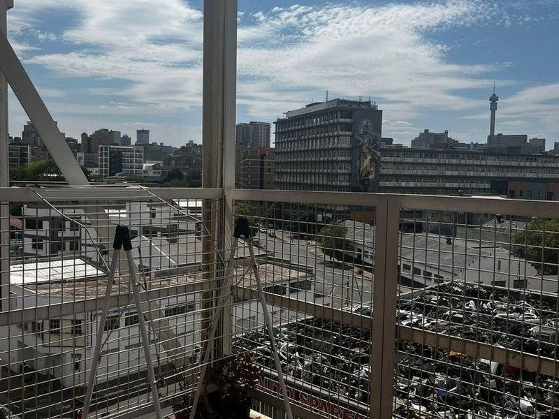 A balcony with metal balustrades and timber decking, offering an elevated urban view of the surrounding city skyline.