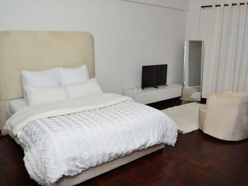 A well-lit bedroom featuring dark parquet flooring and neutral wall finishes, providing a comfortable and functional living space.