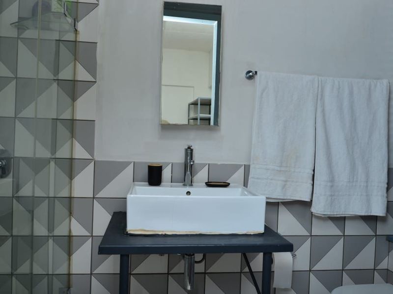 A bathroom featuring a modern vessel sink, chrome faucet, and geometric patterned wall tiles with a glass shower enclosure.