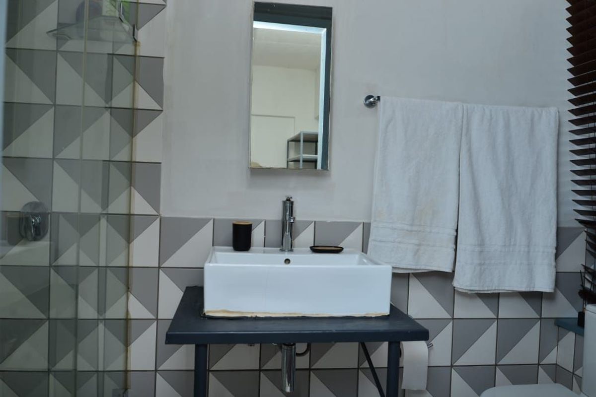 A bathroom featuring a modern vessel sink, chrome faucet, and geometric patterned wall tiles with a glass shower enclosure.