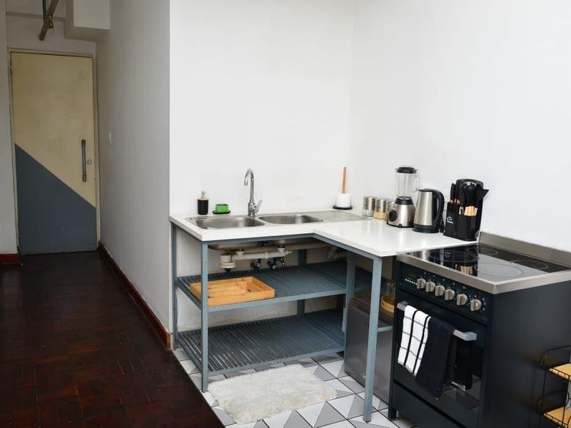 Compact kitchen area featuring a double bowl sink, electric stove with hob, and a mix of parquet and patterned tile flooring.