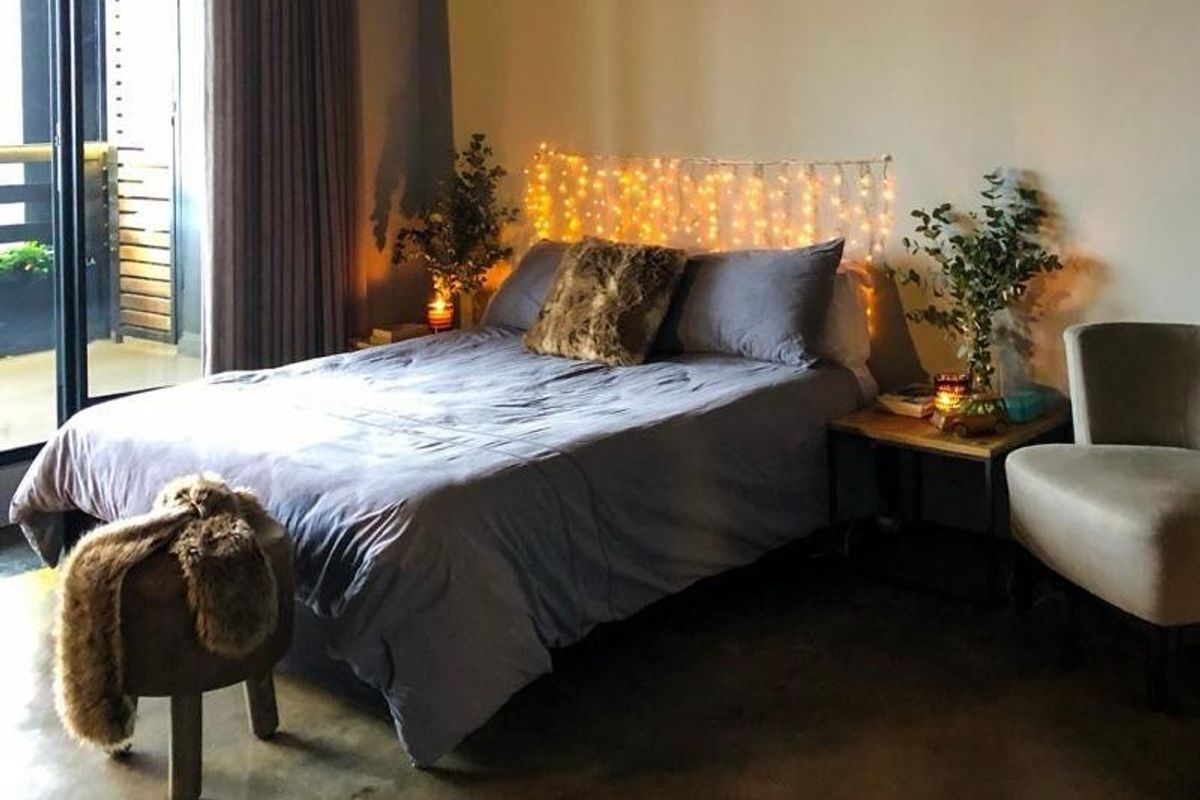 A cozy bedroom featuring polished concrete floors and a large sliding glass door providing access to an outdoor balcony area.