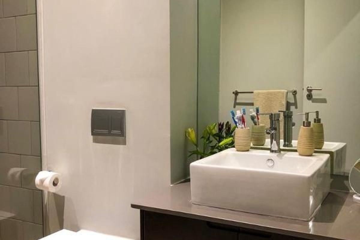 Modern bathroom featuring a vessel sink on a dark vanity cabinet, wall-mounted toilet, and subway tile shower surround.