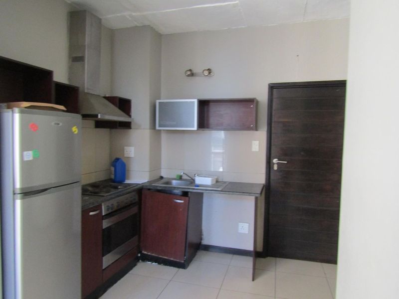 Compact kitchen featuring built-in cabinetry, a stainless steel oven and extractor fan, tiled backsplash, and tiled flooring.