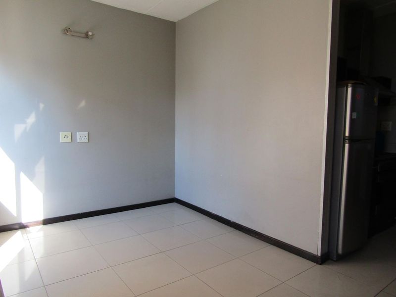 An empty open-plan living area featuring neutral grey walls, tiled flooring, and modern electrical fixtures, providing a blank canvas for interior design.