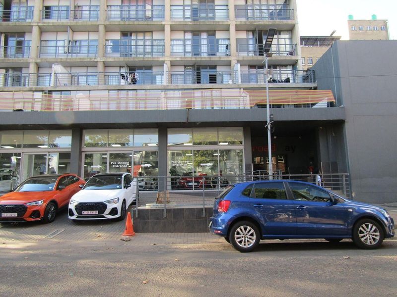 Front elevation of a multi-story apartment building featuring a ground-level commercial storefront and residential balconies with metal railings.