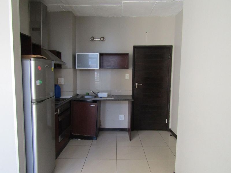 Compact kitchen featuring built-in cabinetry, a stove with extractor fan, tiled flooring, and a tiled backsplash, requiring some maintenance and cosmetic updates.