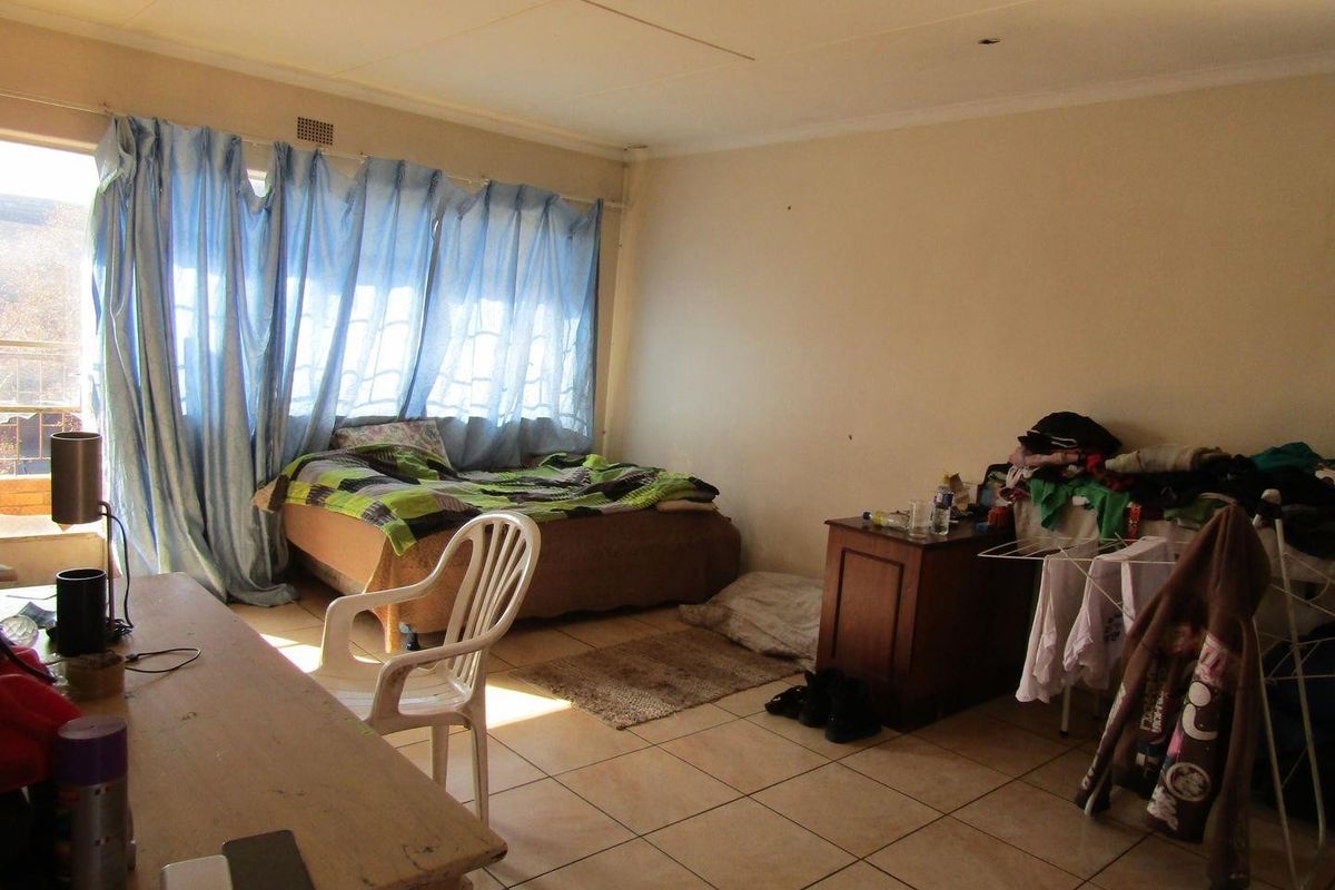 A bedroom featuring tiled flooring and a sliding glass door providing natural light, requiring cosmetic updates to improve the overall condition.