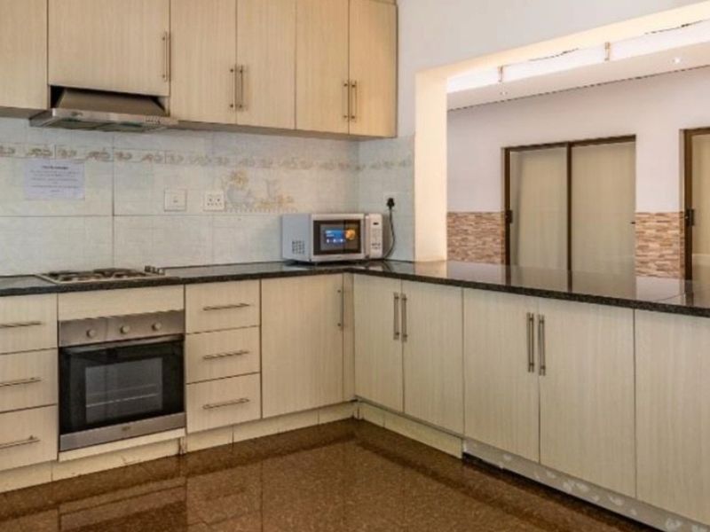 A functional kitchen featuring light wood cabinetry, granite countertops, built-in oven, gas hob, and tiled flooring, offering a clean and practical workspace.