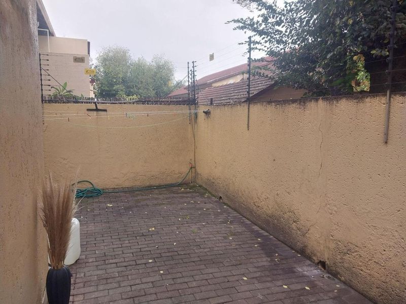 A private rear courtyard area featuring paved flooring, boundary walls with electric fencing, and an external water tap.