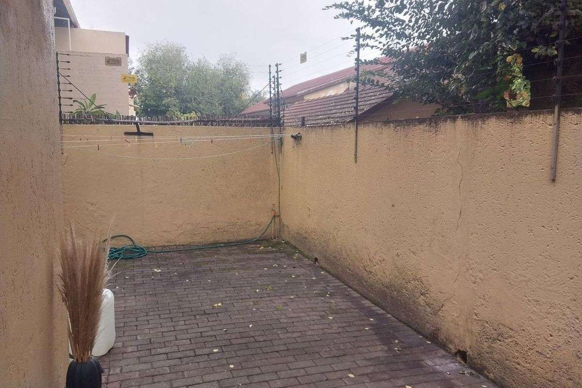 A private rear courtyard area featuring paved flooring, boundary walls with electric fencing, and an external water tap.