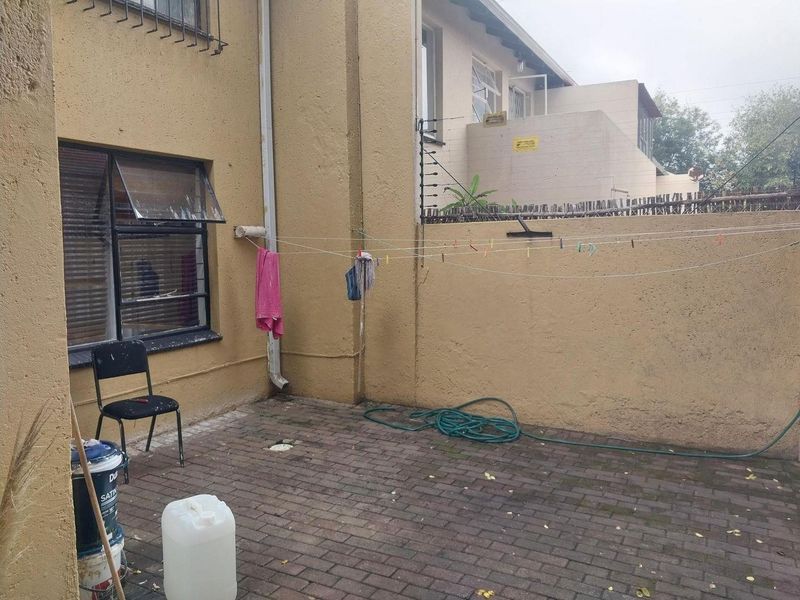 A paved rear courtyard area featuring security fencing and external wall access, providing a functional outdoor space for the apartment.