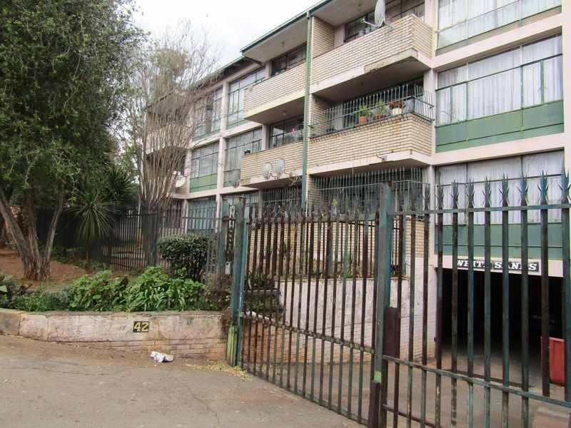 Exterior view of a multi-story apartment building featuring brick facade, private balconies, and secure gated access to underground parking.
