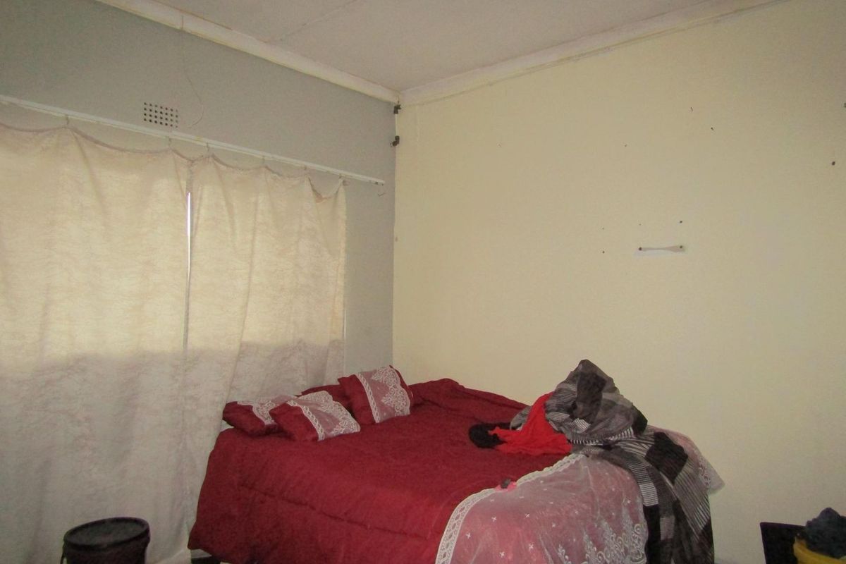 A bedroom featuring a ventilation grille and standard ceiling cornice, currently showing signs of wear on the walls and ceiling.