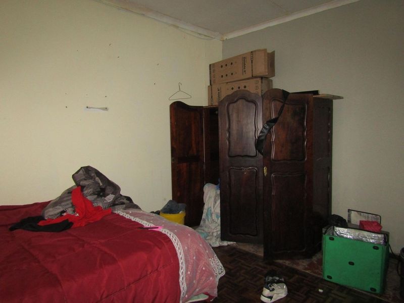 A bedroom featuring plain walls and dark flooring, requiring cosmetic updates and repairs to improve the overall condition and appeal of the space.