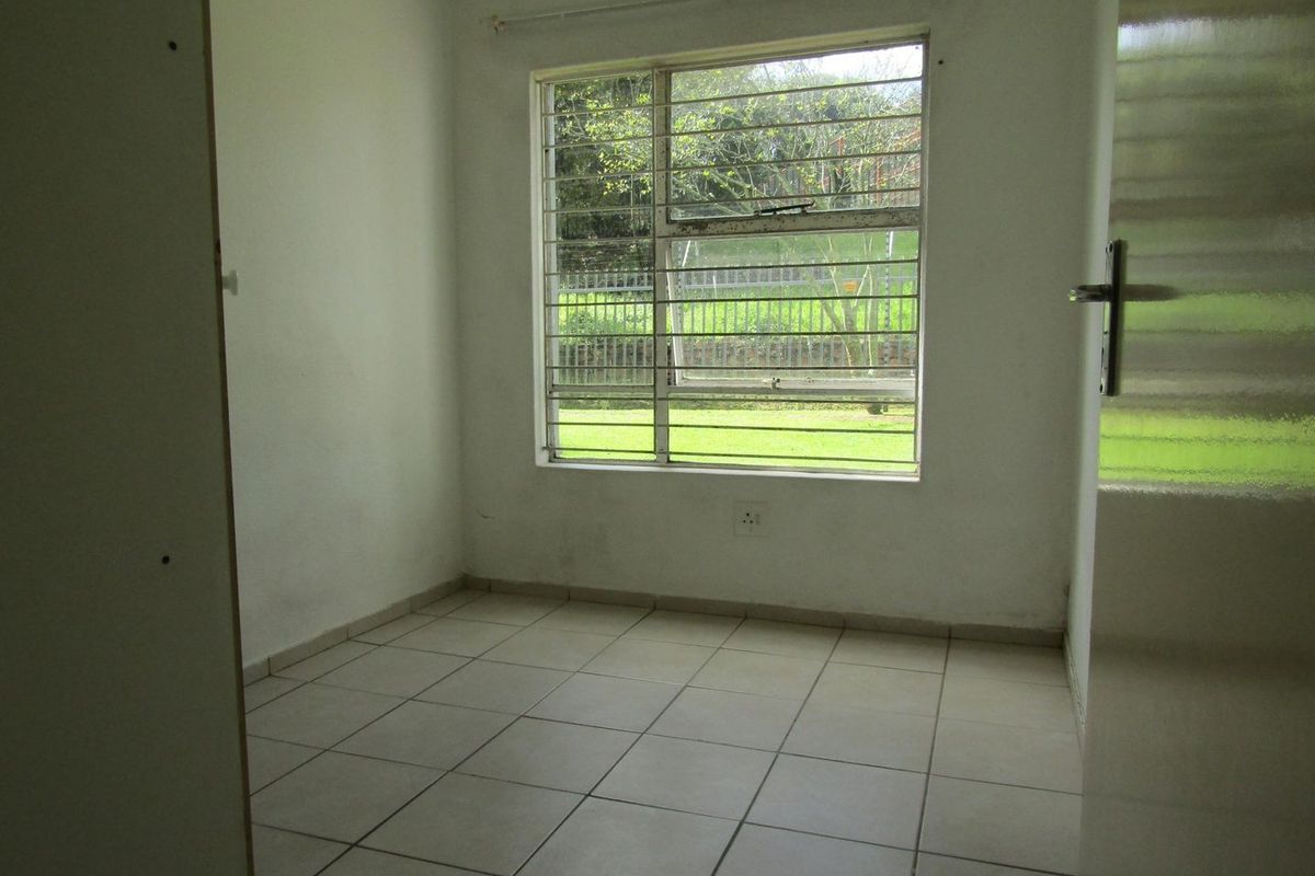 An empty bedroom featuring tiled flooring, a window with security bars, and neutral wall finishes, offering a blank canvas for personalization.
