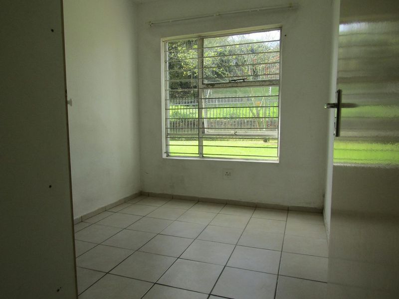 An empty bedroom featuring tiled flooring, a window with security bars, and neutral wall finishes, offering a blank canvas for personalization.