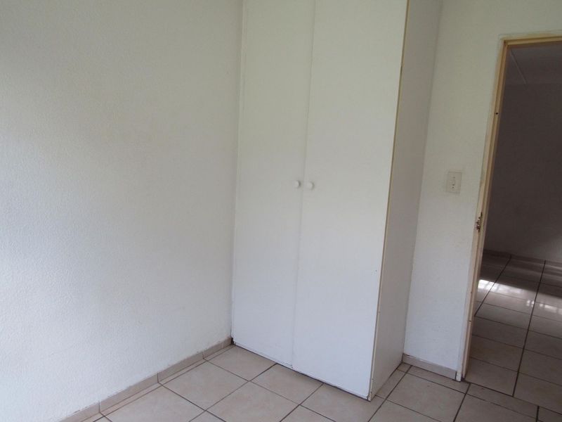 An empty bedroom featuring tiled flooring and a built-in cupboard, offering a blank canvas for personalization.