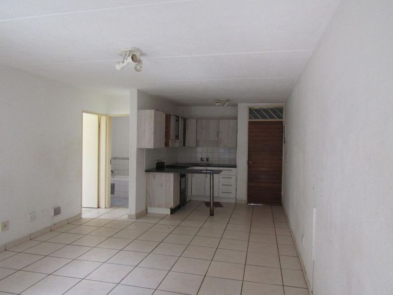 An open-plan living and kitchen area featuring tiled flooring, built-in cabinetry, and direct access to an adjacent bathroom.