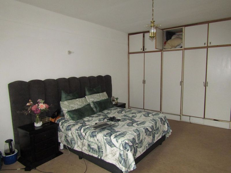 A spacious bedroom featuring extensive built-in cupboards and neutral carpeting, offering a functional layout ready for modern updates.