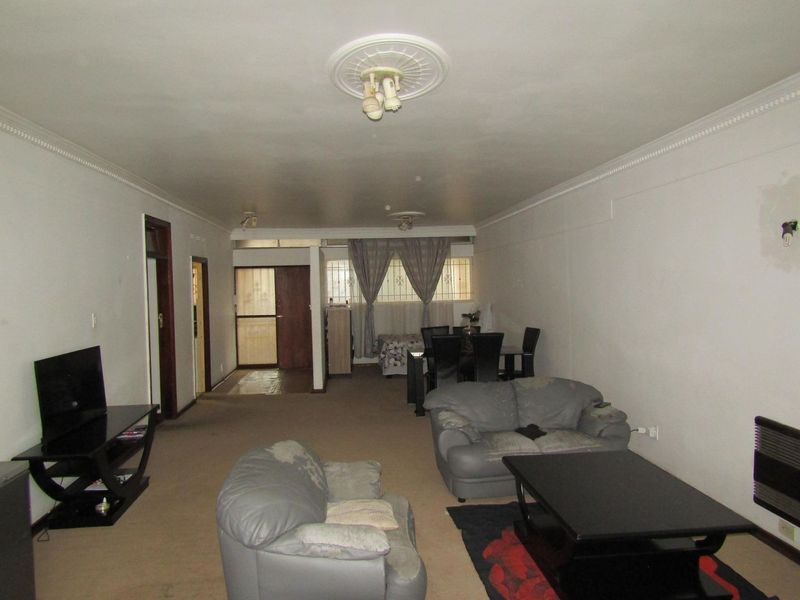 Spacious open-plan living and dining area featuring decorative ceiling roses, cornices, and a wall-mounted heater, offering a versatile layout for modern living.