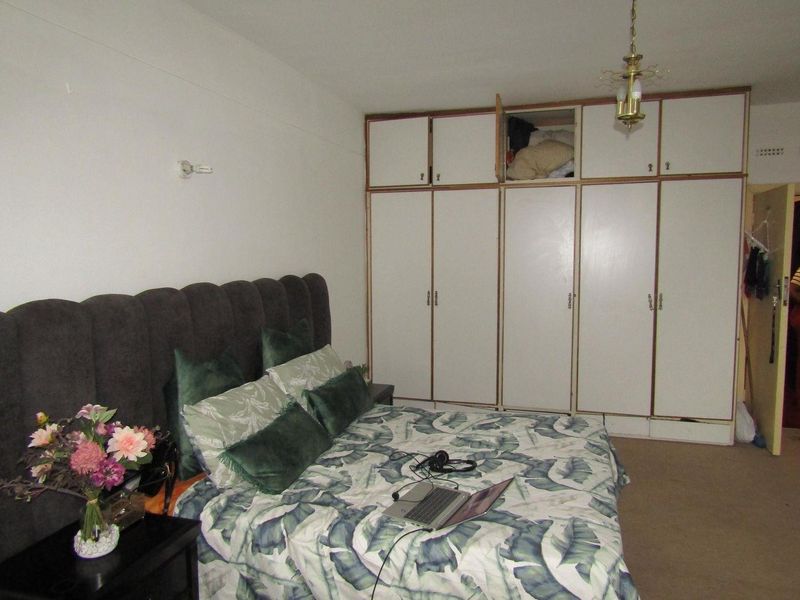 Bedroom featuring extensive built-in storage cupboards and carpeted flooring, requiring some maintenance to the cabinetry and finishes.
