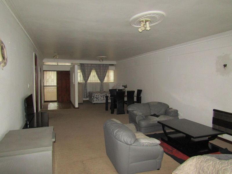 Spacious open-plan living and dining area featuring decorative ceiling roses, coving, and a wall-mounted heater, offering a versatile layout for modern living.