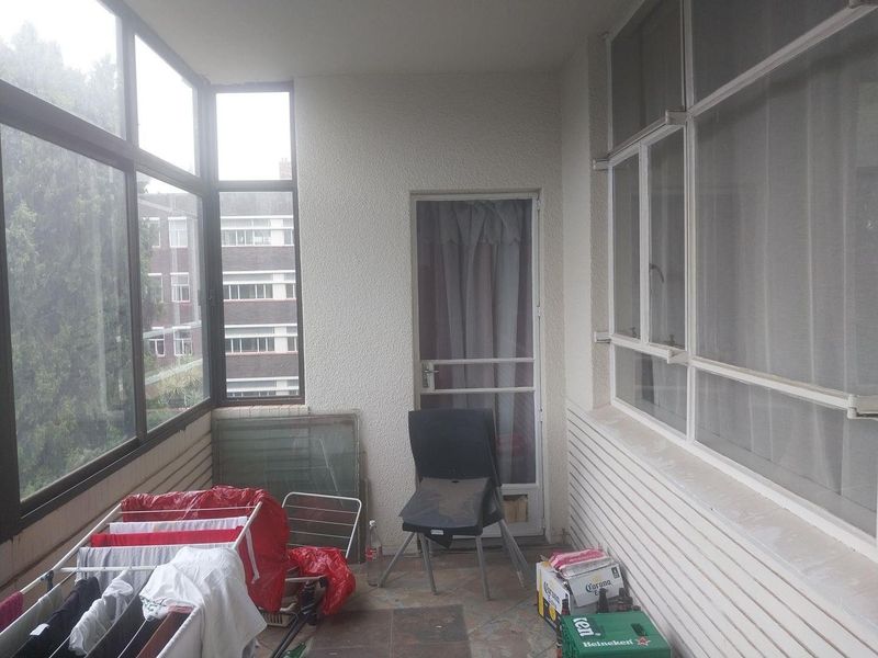 An enclosed balcony area featuring large windows and tiled flooring, offering a versatile space that could be repurposed as a sunroom or study.