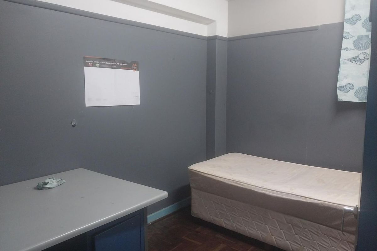 A compact bedroom featuring dark grey walls, parquet flooring, and a built-in desk area, offering a functional space ready for modernization.