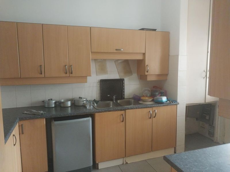 A functional kitchen featuring laminate cabinetry, a double bowl stainless steel sink, and tiled splashbacks, offering a practical layout for daily use.