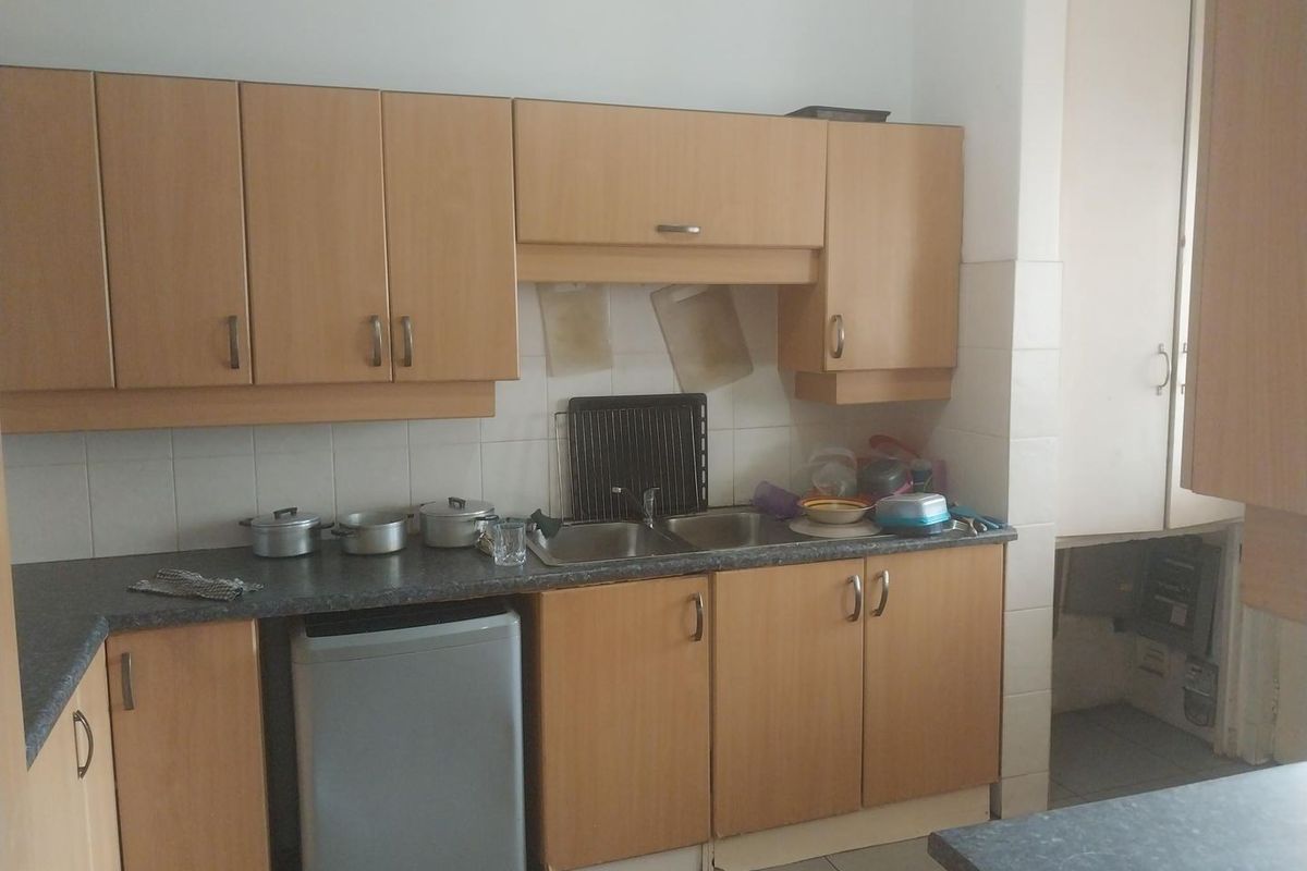 A functional kitchen featuring laminate cabinetry, a double bowl stainless steel sink, and tiled splashbacks, offering a practical layout for daily use.