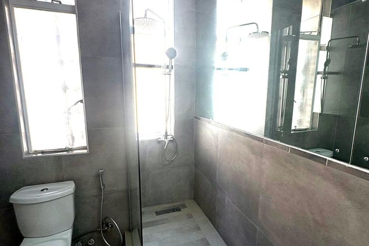 Modern bathroom featuring a walk-in shower with glass screen, large wall mirror, tiled finishes, and contemporary sanitary ware.